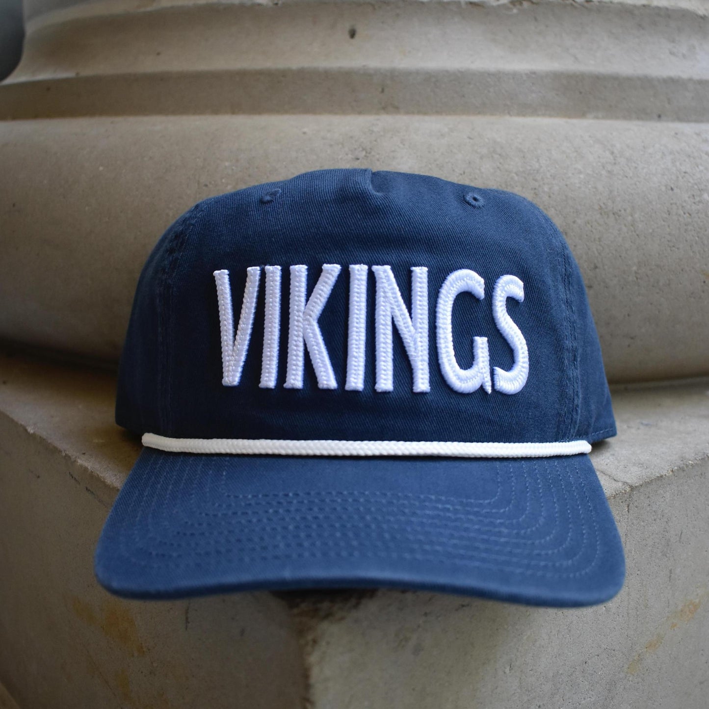 A navy blue baseball cap with 'VIKINGS' embroidered in white across the front