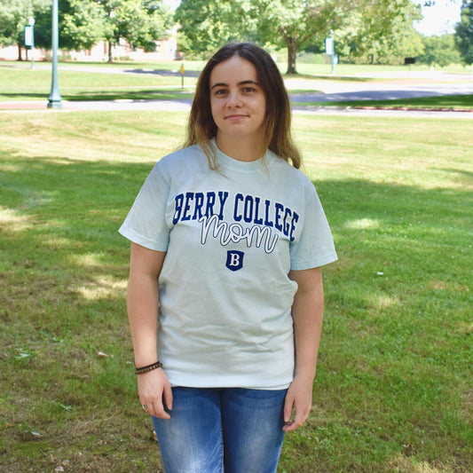 Woman wearing Light blue shirt with "berry College" above the word "mom" and the Berry Shield on the bottom